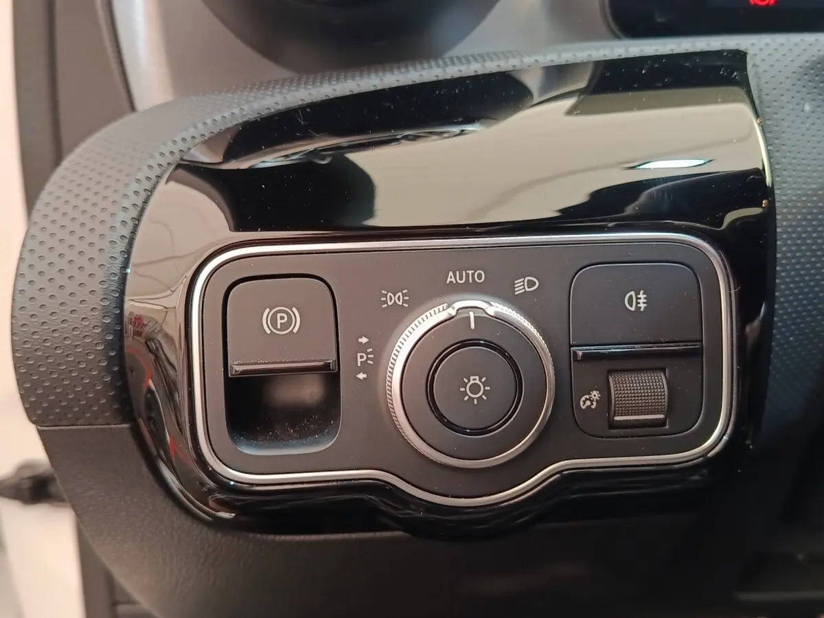 Gros plan sur le panneau de commande des phares et du frein à main électrique de la Mercedes Classe A blanche.