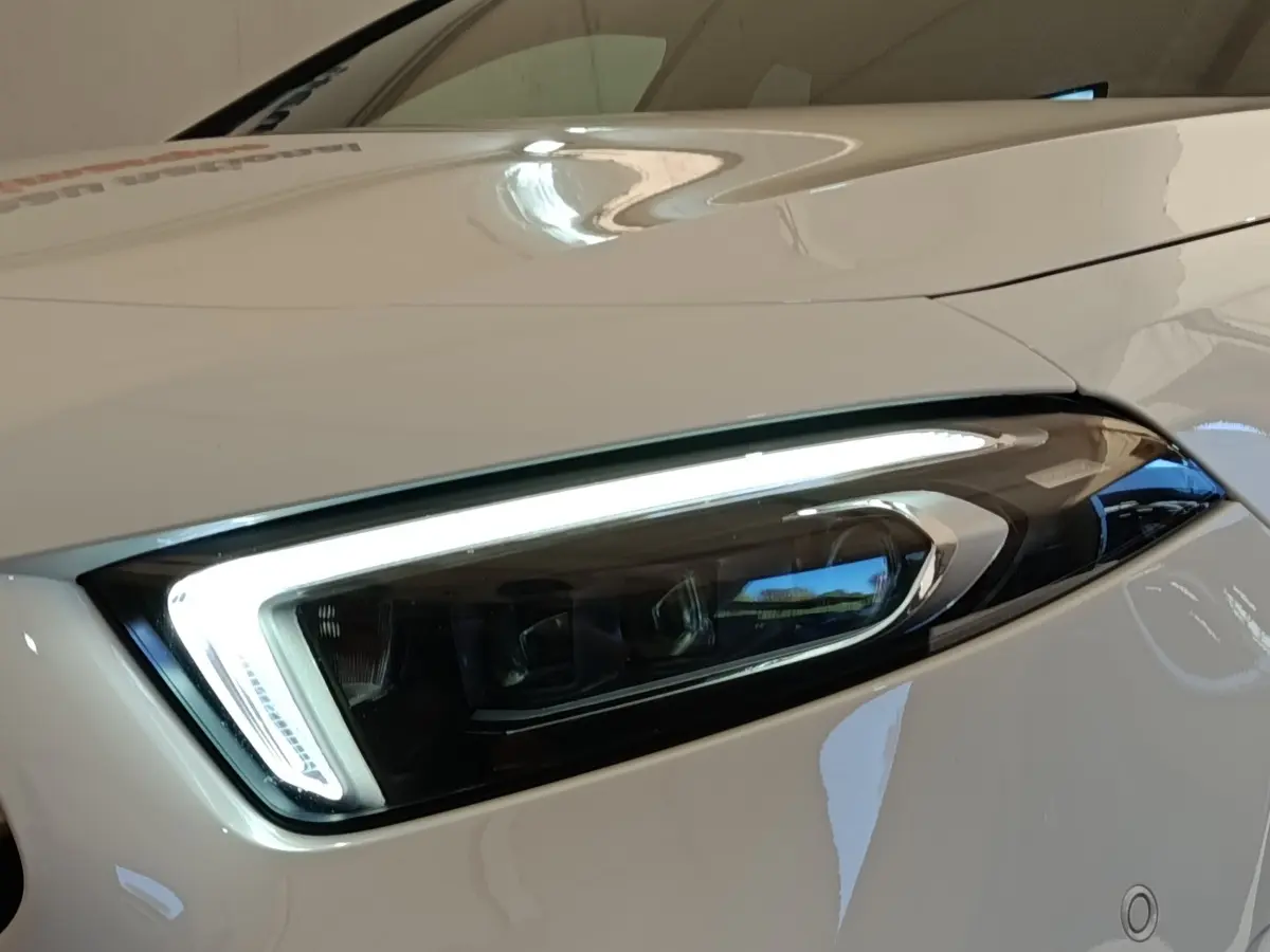 Gros plan sur le phare avant droit LED d’une Mercedes Classe A blanche, soulignant son design moderne et précis.