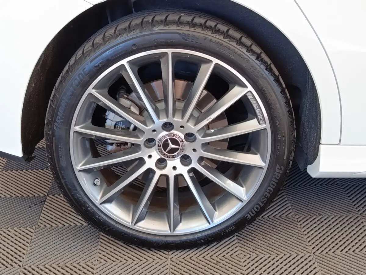 Gros plan sur la roue avant droite argentée AMG d'une Mercedes Classe A blanche, avec pneu Bridgestone visible.