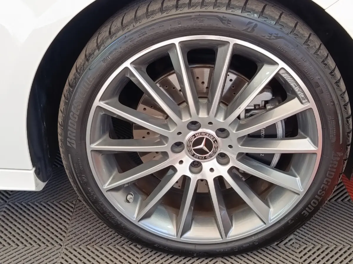 Gros plan sur la jante AMG argentée de la Mercedes Classe A blanche, avec pneu Bridgestone visible.