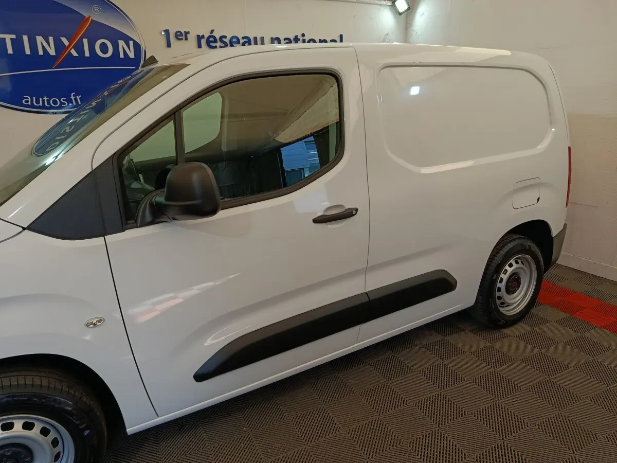 Vue de profil côté gauche du Peugeot Partner blanc, utilitaire compact avec protections latérales noires et jantes acier.