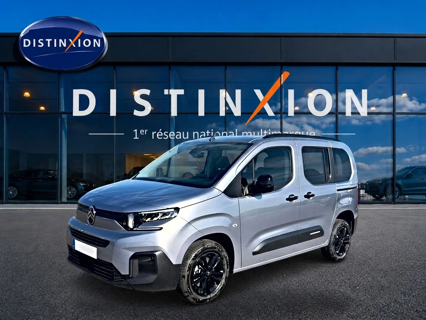 Vue 3/4 avant droite d'un Citroën Berlingo 2026 gris acier avec jantes noires et protections latérales noires.