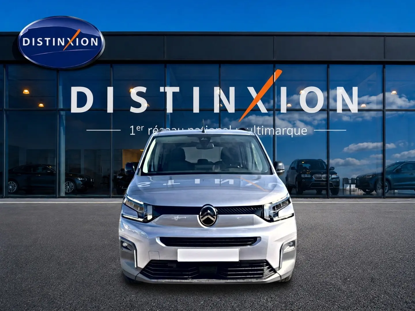 Vue avant d'un Citroën Berlingo 2026 gris acier, avec phares LED et calandre noire devant un showroom Distinxion.