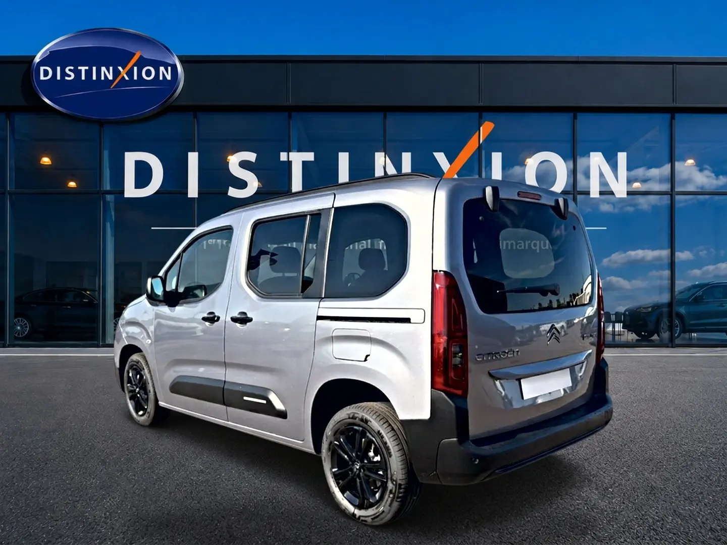 Vue 3/4 arrière droite du Citroën Berlingo N1 steel grey avec jantes noires devant un showroom Distinxion.