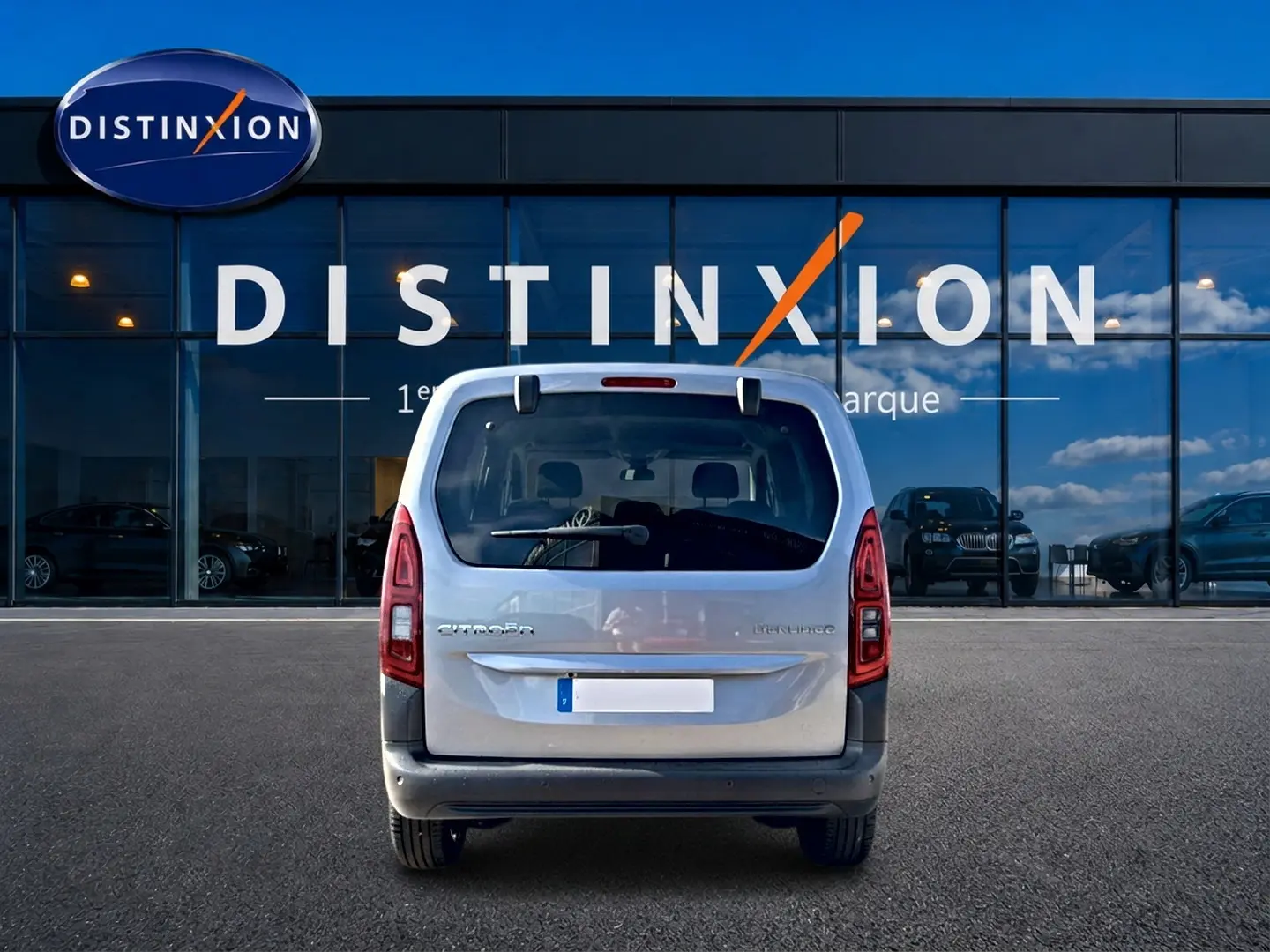 Vue arrière d'un Citroën Berlingo Steel Grey 2026 stationné devant une vitrine avec logo Distinxion.