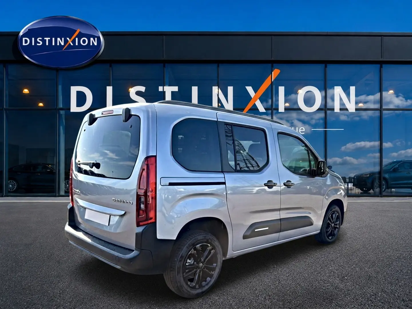 Vue 3/4 arrière droite du Citroën Berlingo Steel Grey 2026 avec barres de toit et jantes alu noires.
