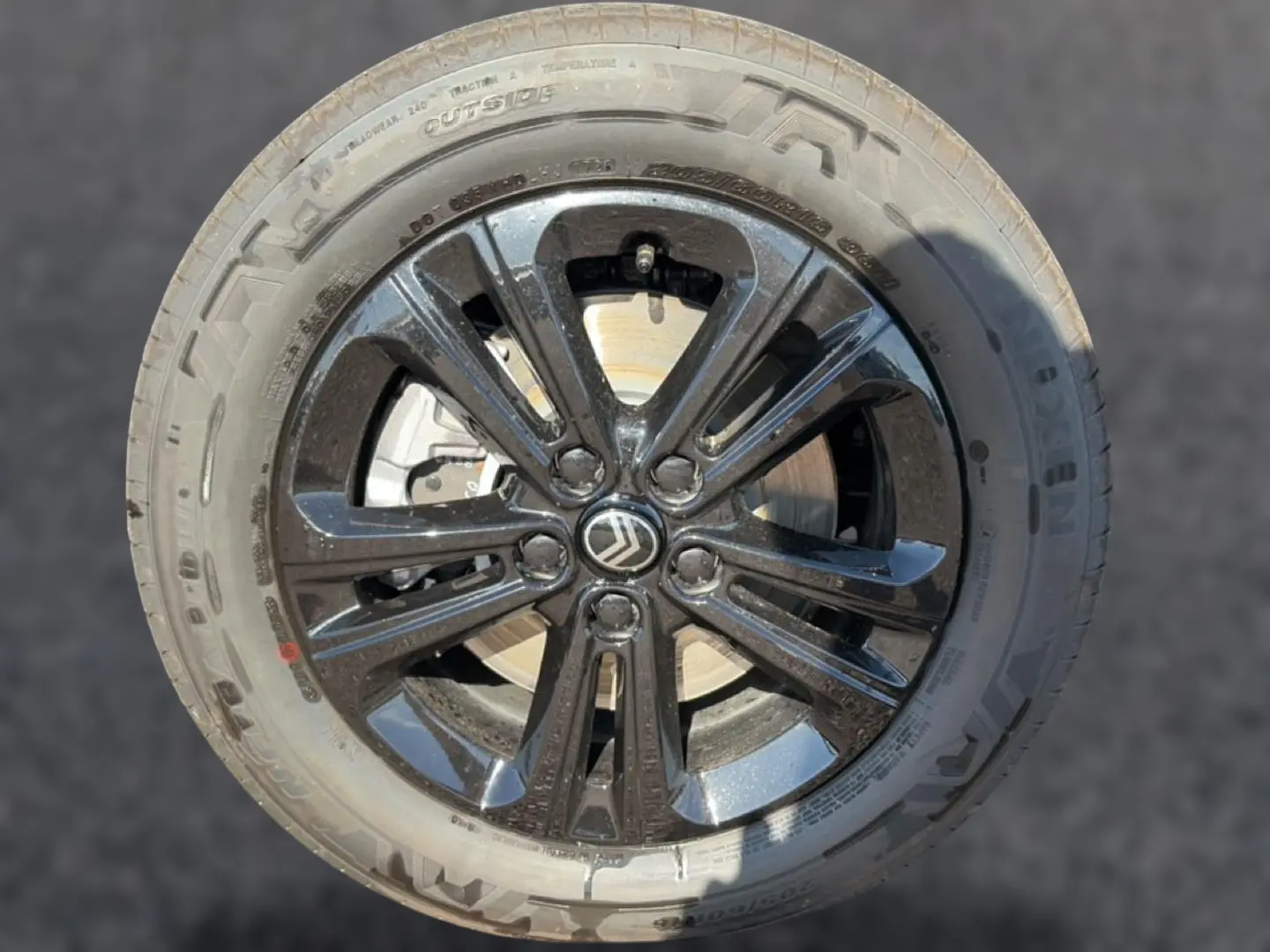 Gros plan sur la jante noire brillante avec logo Citroën au centre, montée sur pneu Nexen Steel Grey.