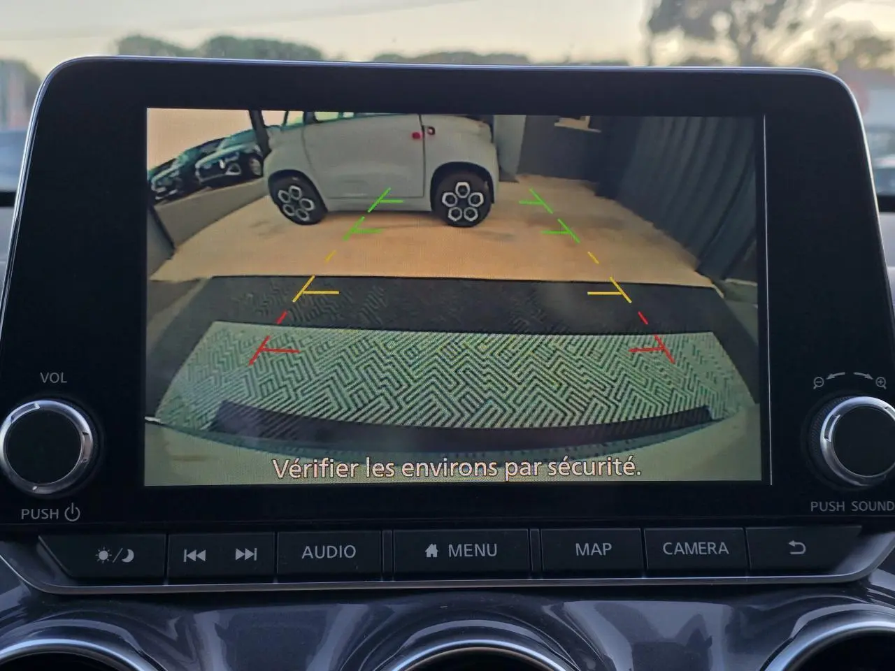 Écran de caméra de recul du Nissan Juke II bleu magnetic montrant l'arrière avec lignes de guidage colorées.