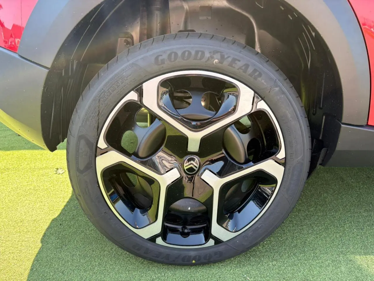 Gros plan sur la roue avant droite d'une Citroën C3 rouge Elixir avec jante noire et argentée au design moderne.