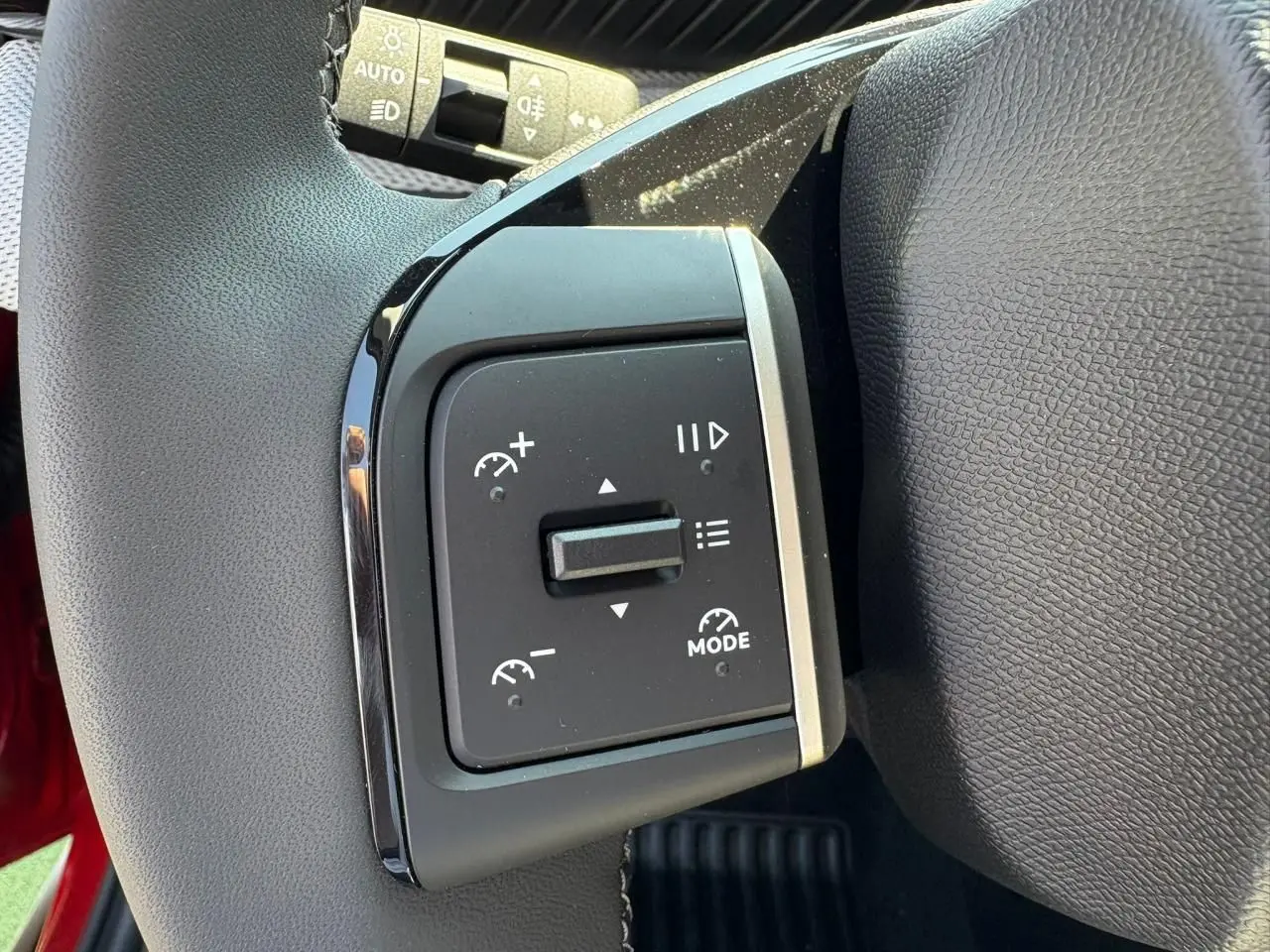 Gros plan sur les commandes de régulateur de vitesse au volant d'une Citroën C3 rouge Elixir toit noir.