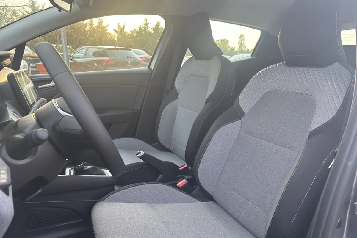 Vue intérieure côté gauche de la Renault Clio 2025 gris schiste, mettant en valeur les sièges tissu gris à motifs géométriques.