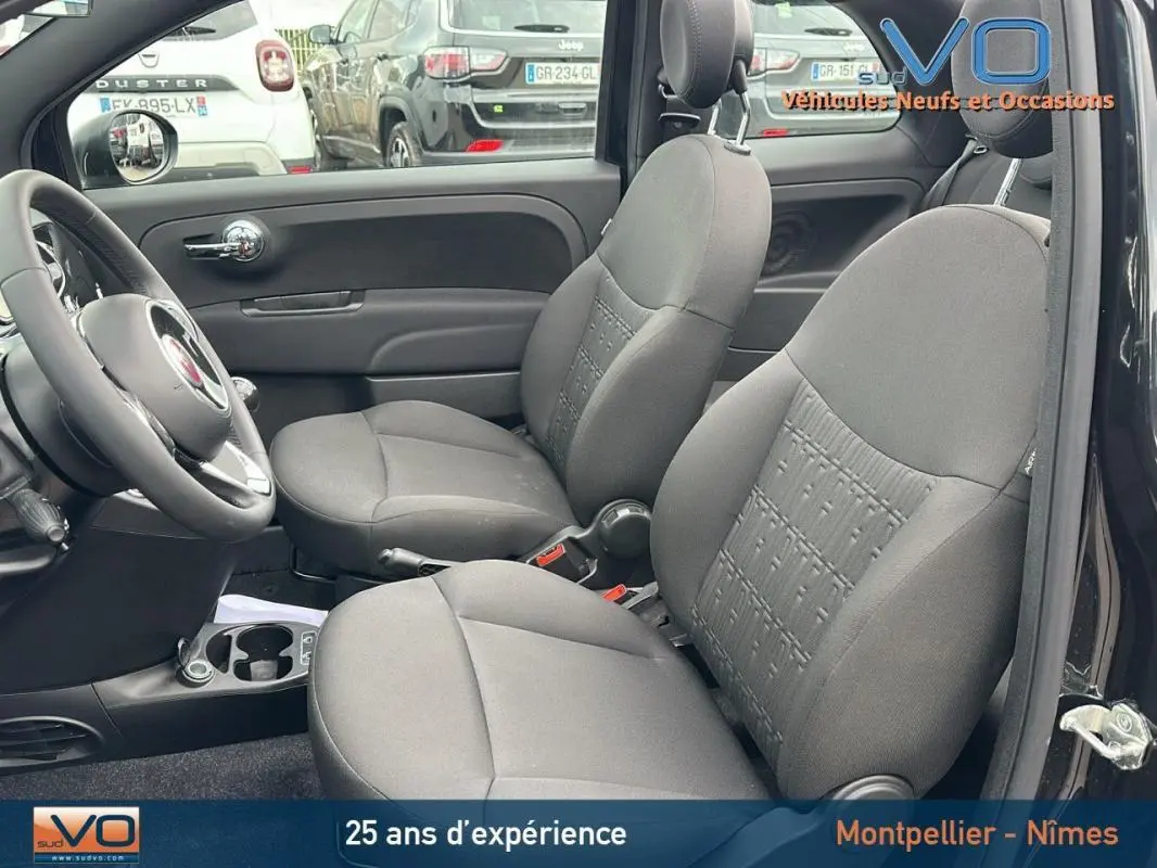 Vue intérieure côté conducteur de la FIAT 500C noire 2024, sièges avant en tissu gris et volant visible.