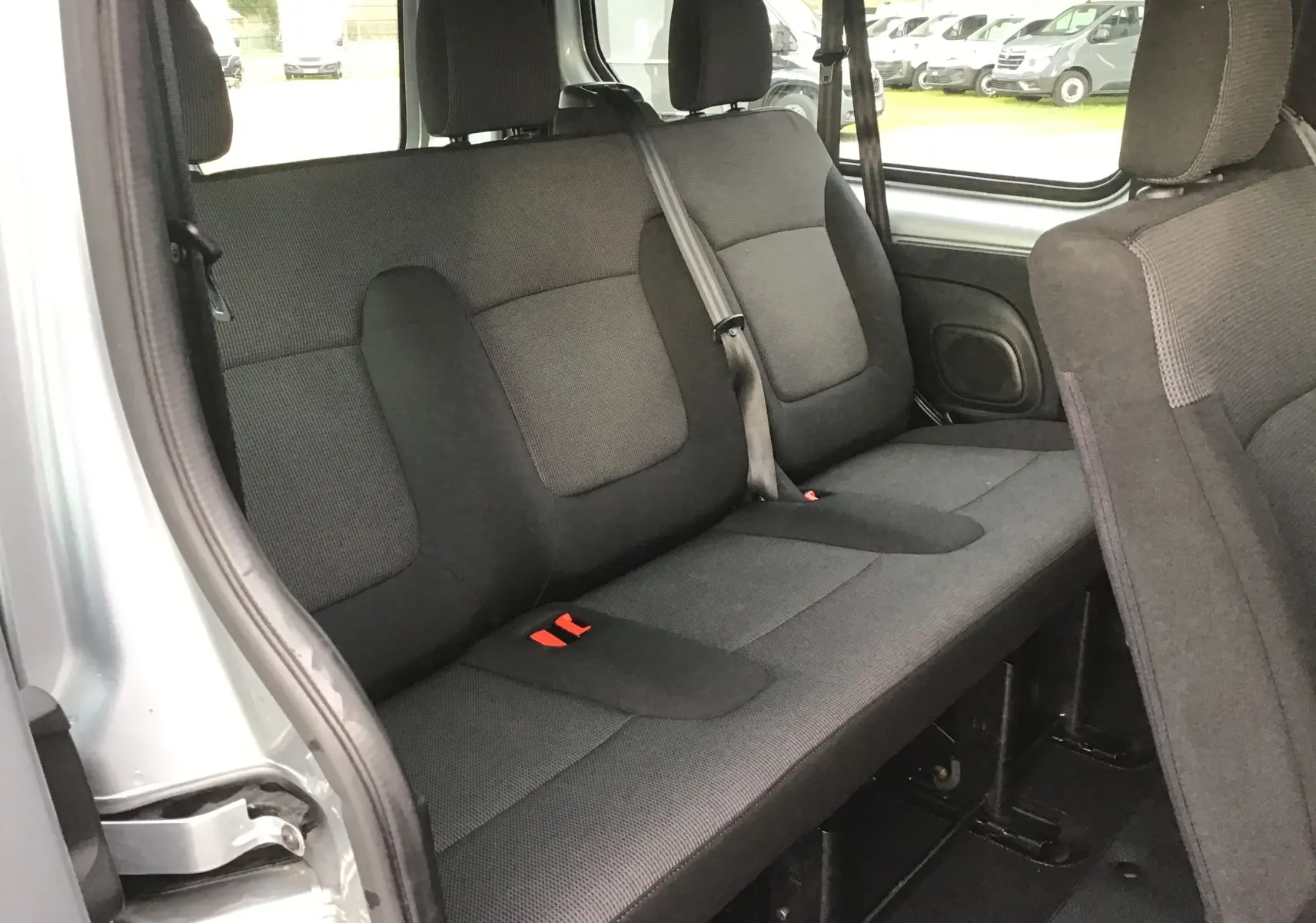 Vue intérieure côté gauche montrant la banquette arrière grise du Renault Trafic Combi L2 2022, avec ceintures de sécurité visibles.