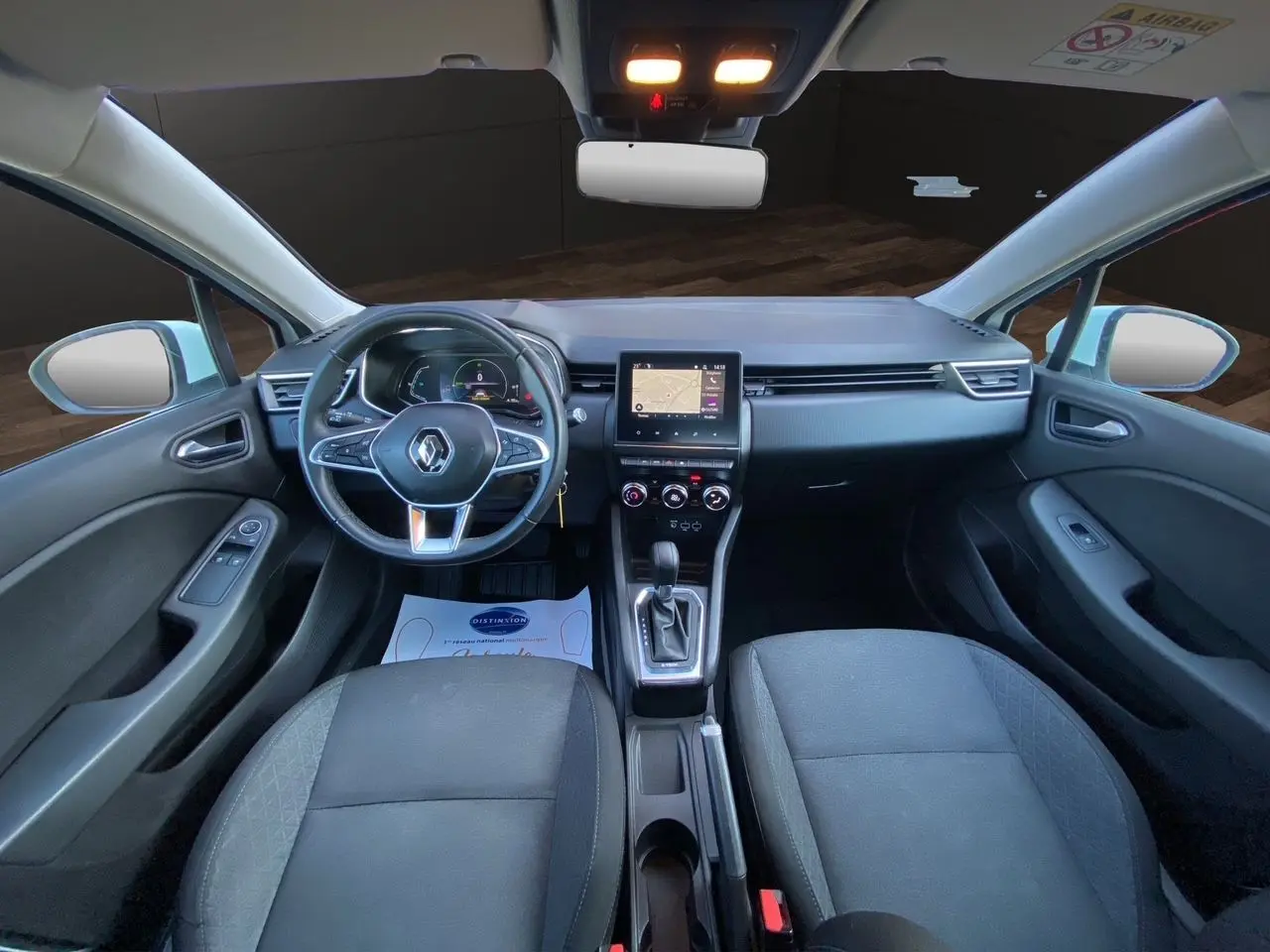 Vue intérieure avant de la Renault Clio V E-Tech 140 Business avec tableau de bord noir et écran tactile central.