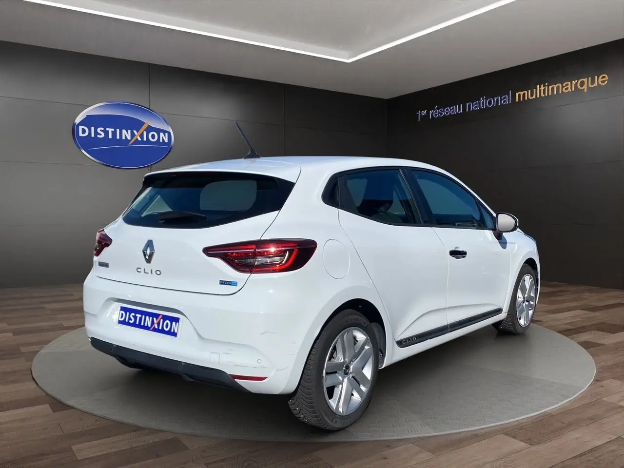 Vue 3/4 arrière droite d'une Renault Clio V blanche hybride, avec jantes alliage et logo E-TECH visible sur le hayon.