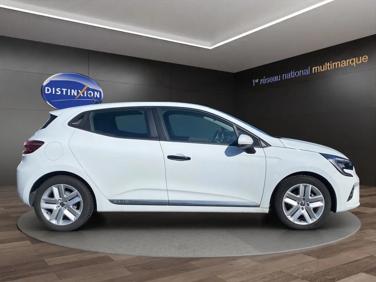 Profil droit de la Renault Clio V blanche hybride, version Business Société, avec jantes alliage et vitres teintées.