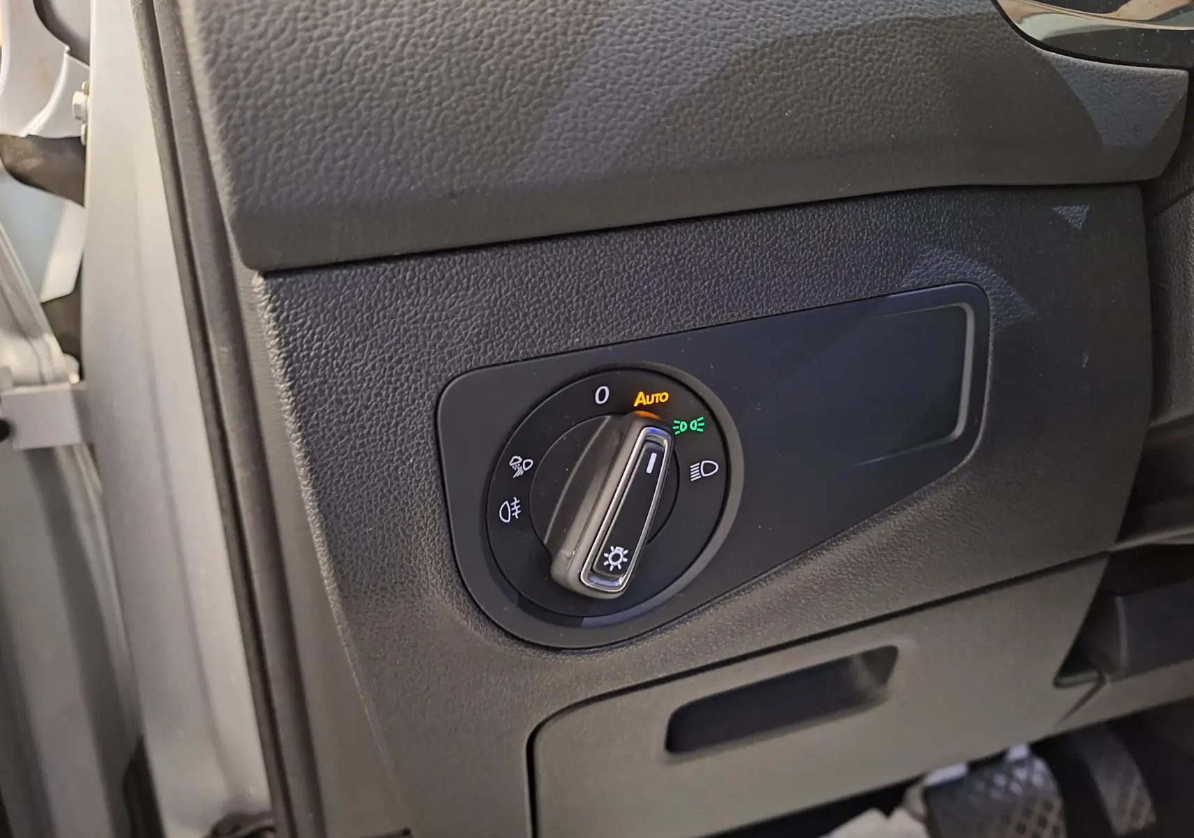 Gros plan sur le commutateur d'éclairage noir du tableau de bord côté gauche du Volkswagen Tiguan gris 2021.