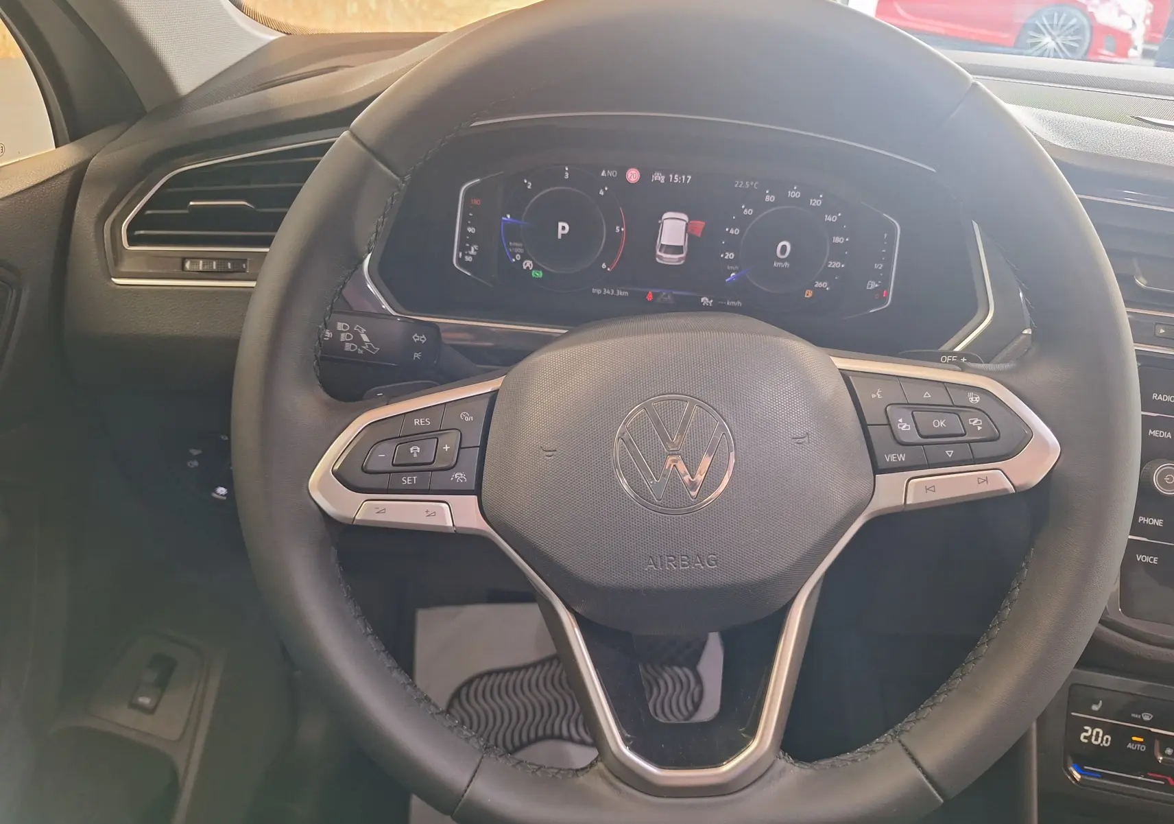 Vue rapprochée du volant cuir multifonction du Volkswagen Tiguan gris, avec tableau de bord digital allumé.