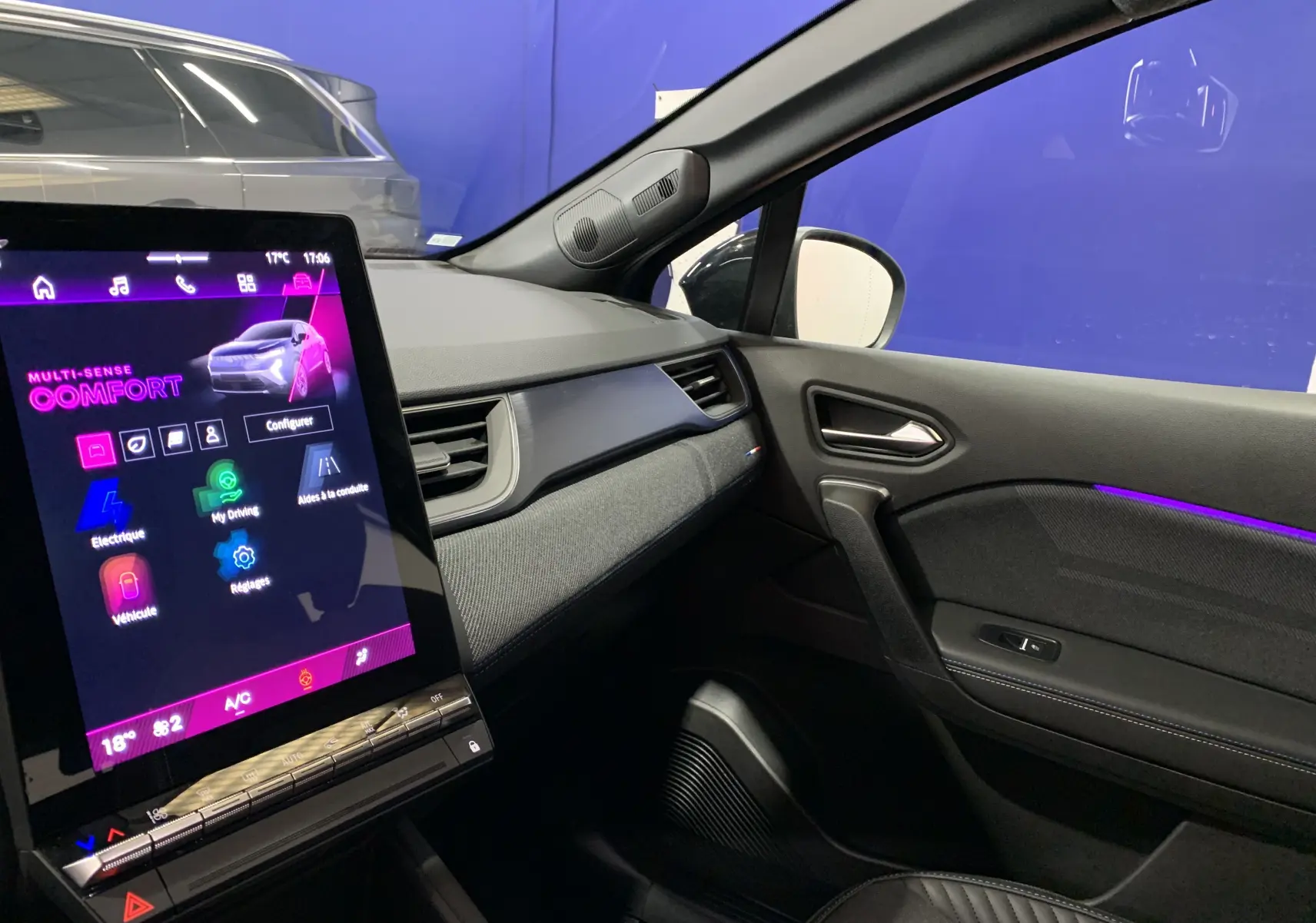 Intérieur de la Renault Symbioz E-Tech hybride 2025, vue côté passager avec écran tactile et éclairage d'ambiance violet.
