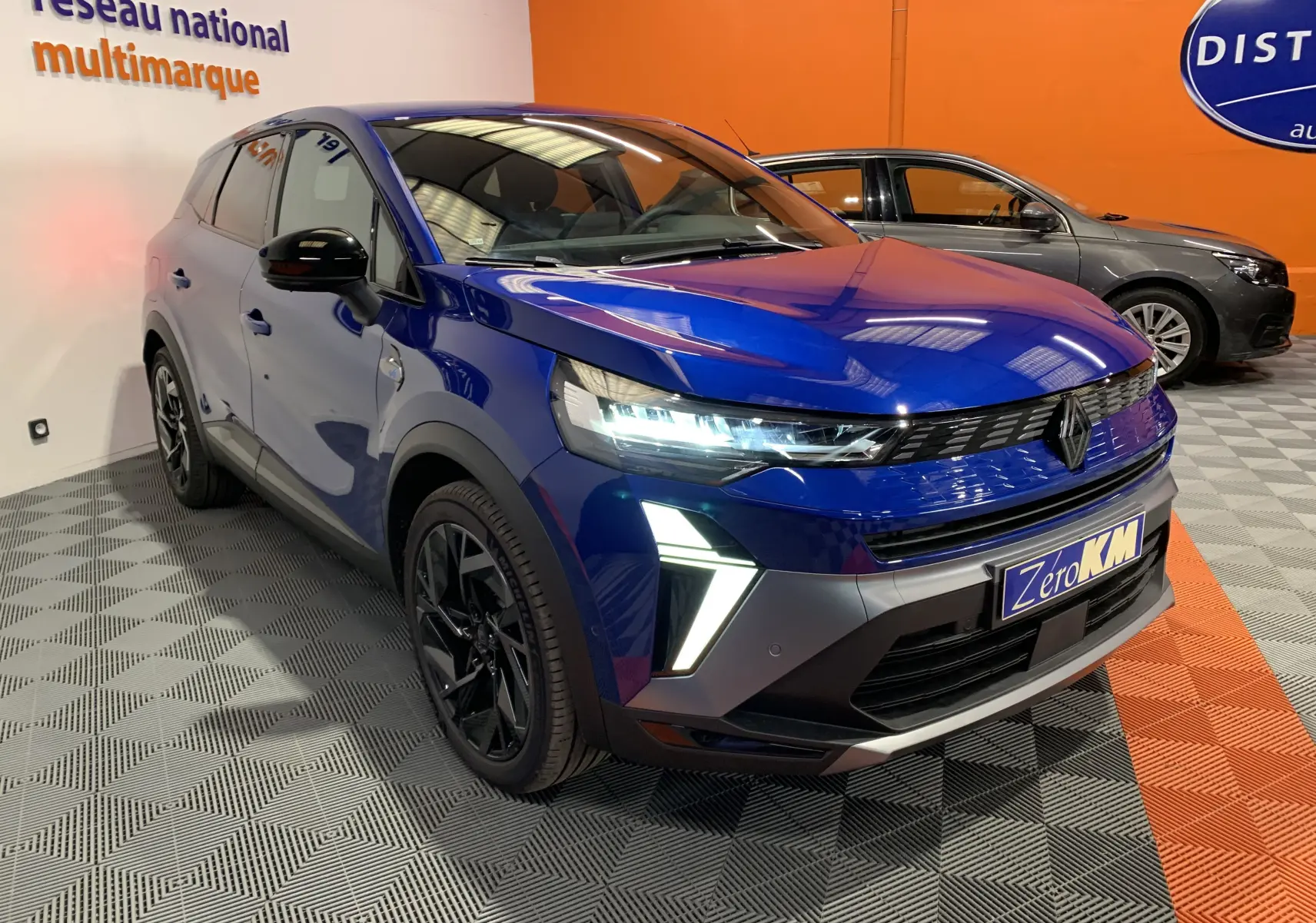 Renault Symbioz E-Tech hybride bleu iron en 3/4 avant droit, avec feux LED et jantes noires distinctives.