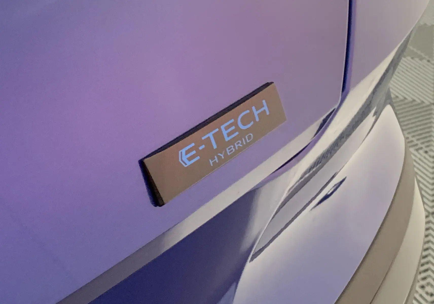 Gros plan sur l'arrière droit bleu iron du Renault Symbioz 2025 avec le badge E-TECH Hybrid visible.