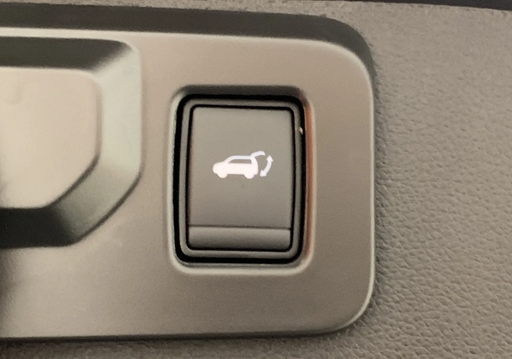 Bouton intérieur noir avec symbole blanc d'ouverture du hayon motorisé sur Renault Symbioz Bleu Iron.