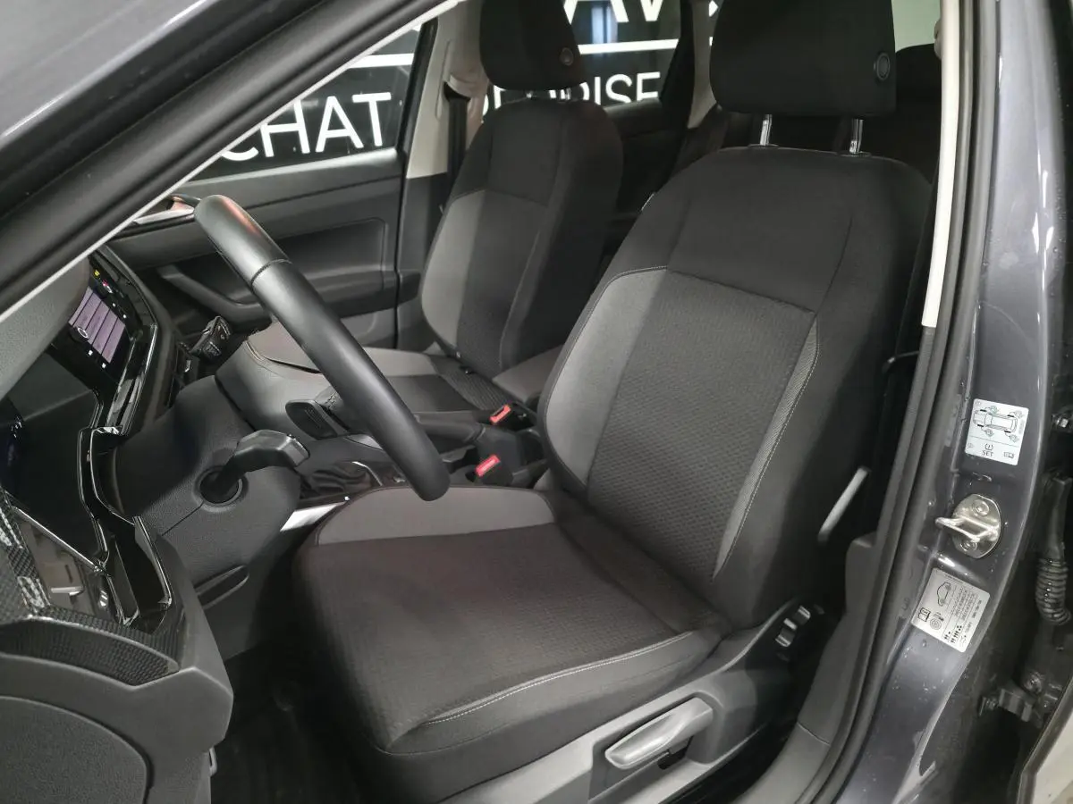 Vue intérieure côté conducteur de la Volkswagen Polo gris, avec sièges tissu noir et volant multifonction cuir.