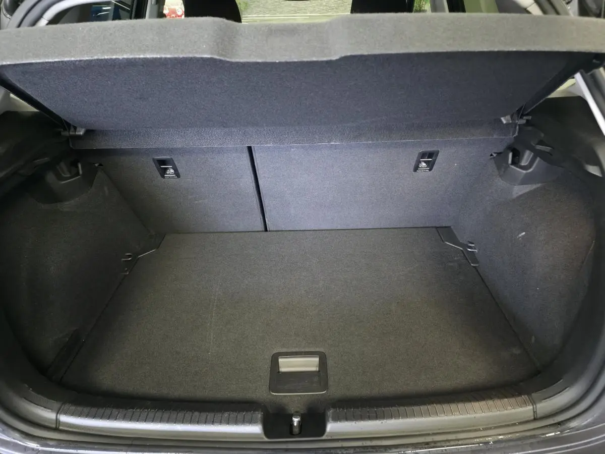 Coffre ouvert vu de l'arrière d'une Volkswagen Polo gris, montrant l'espace de chargement et la banquette arrière rabattable.