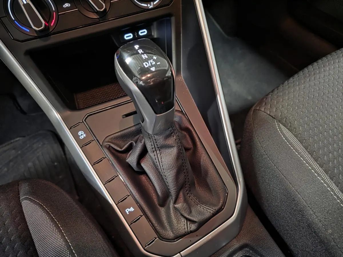 Gros plan sur levier de vitesses automatique noir et console centrale grise dans Volkswagen Polo gris 2025.