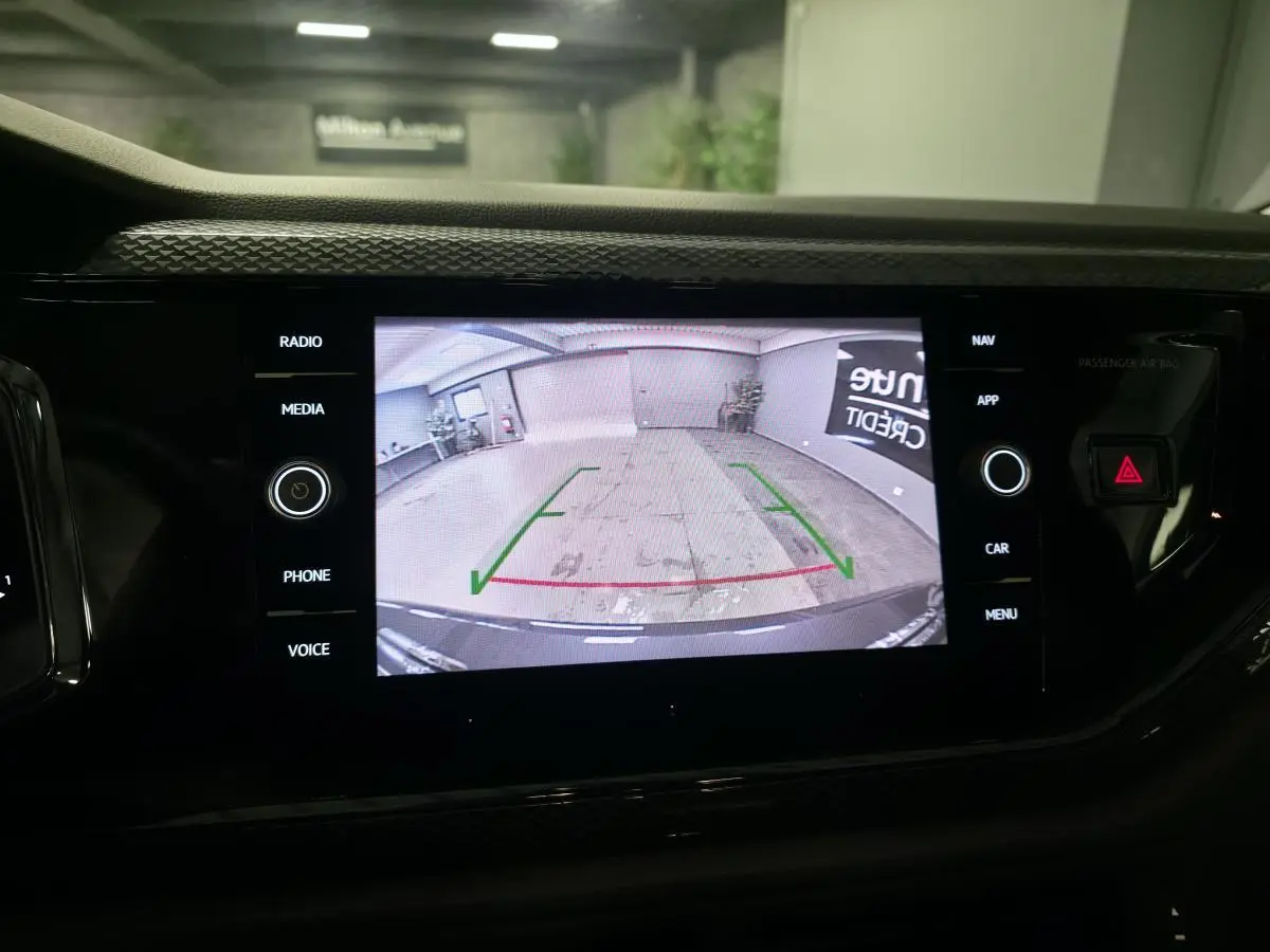 Écran tactile central affichant la caméra de recul d'une Volkswagen Polo grise, vue intérieure du tableau de bord.