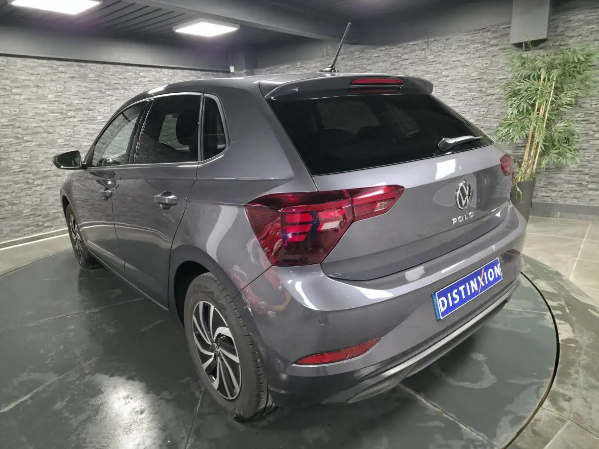 Vue 3/4 arrière gauche d'une Volkswagen Polo gris métallisé avec jantes alliage et vitres surteintées.