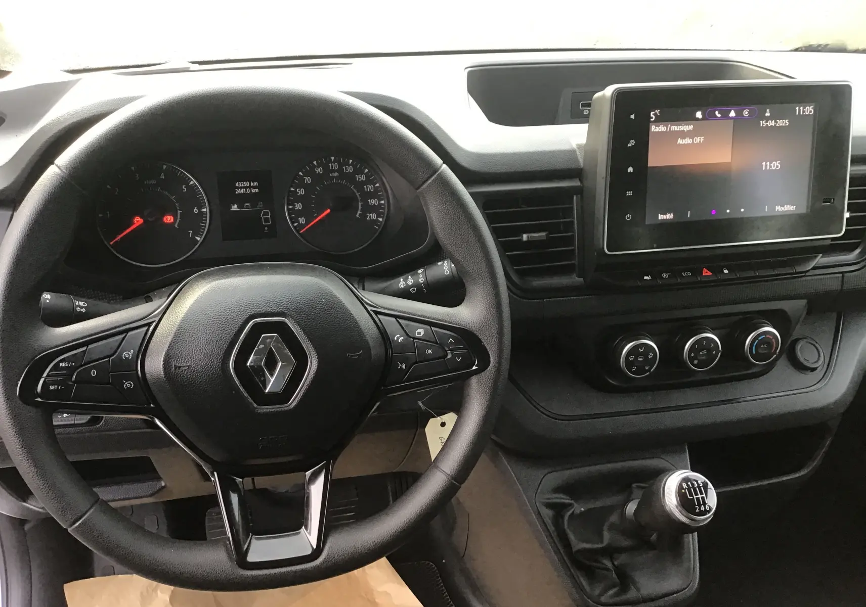 Vue intérieure centrée sur le volant Renault et la console avec écran tactile et levier de vitesse manuel du Trafic Combi gris clair.