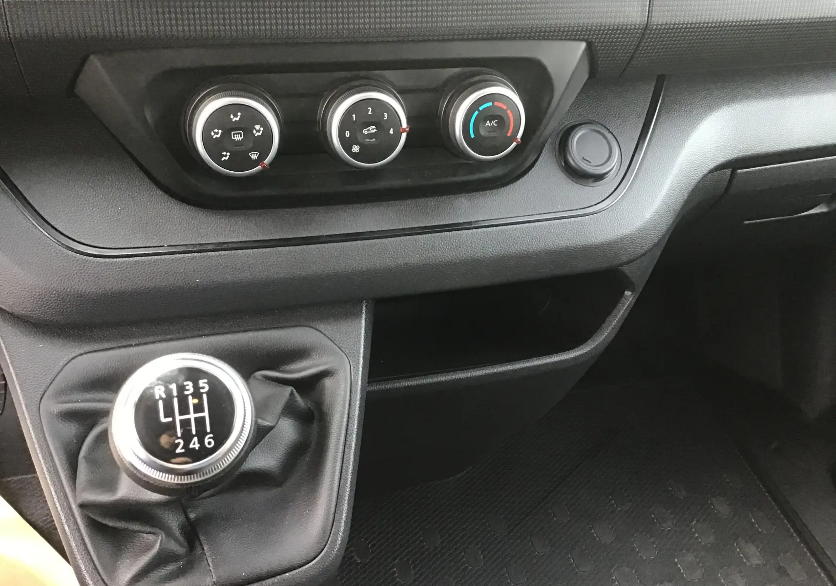 Gros plan sur la console centrale du Renault Trafic Combi 2023, avec levier de vitesses manuel et commandes de climatisation.