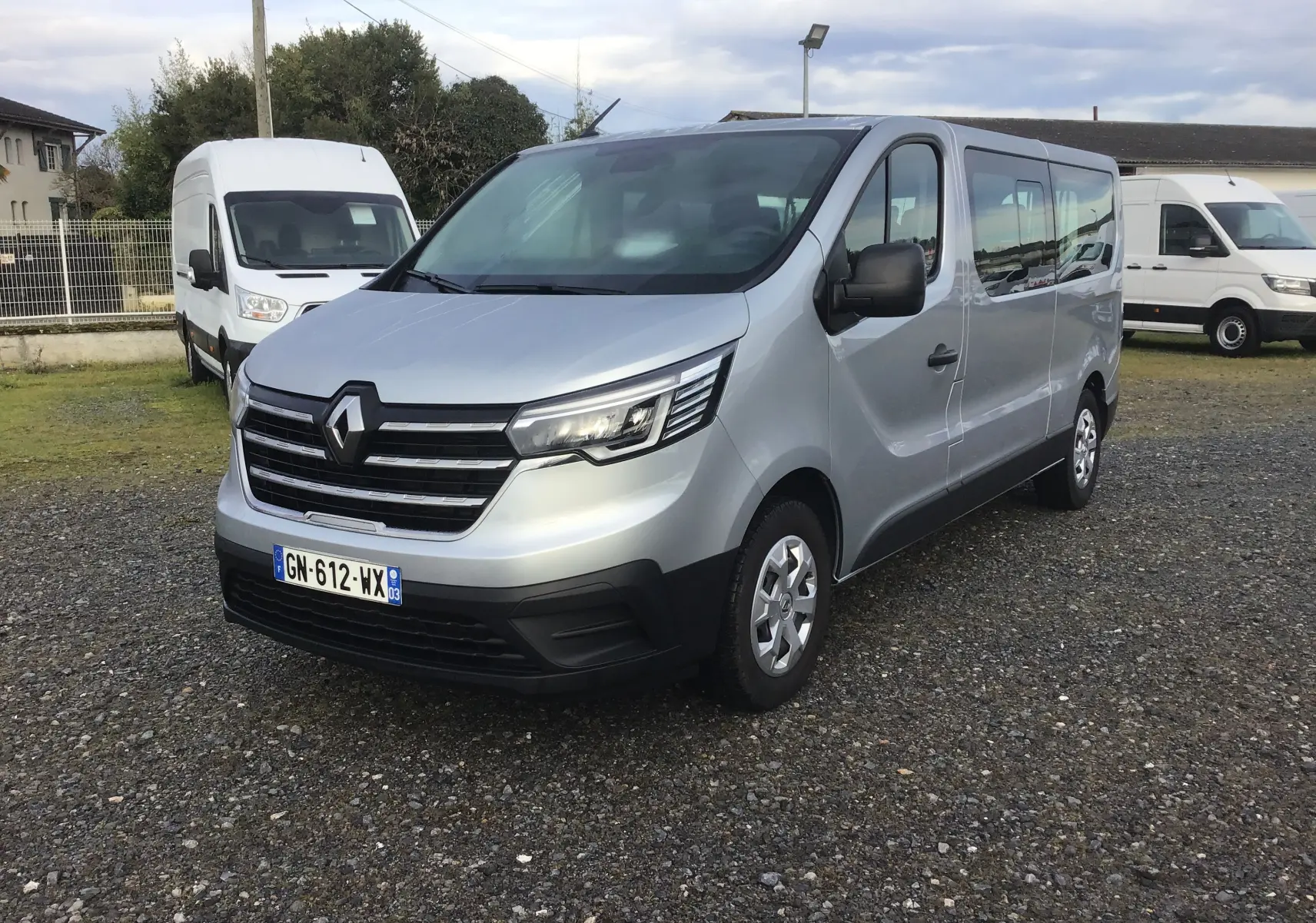 Vue 3/4 avant d'un Renault Trafic Combi gris clair métal 2023, avec calandre noire et jantes acier argentées.
