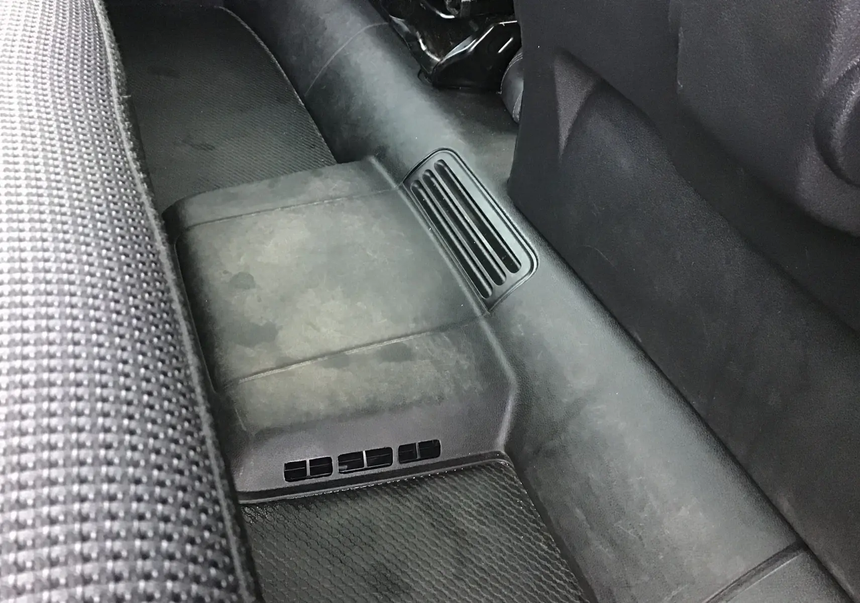 Vue rapprochée du plancher arrière côté gauche du Renault Trafic Combi gris clair, montrant les grilles d’aération au sol.