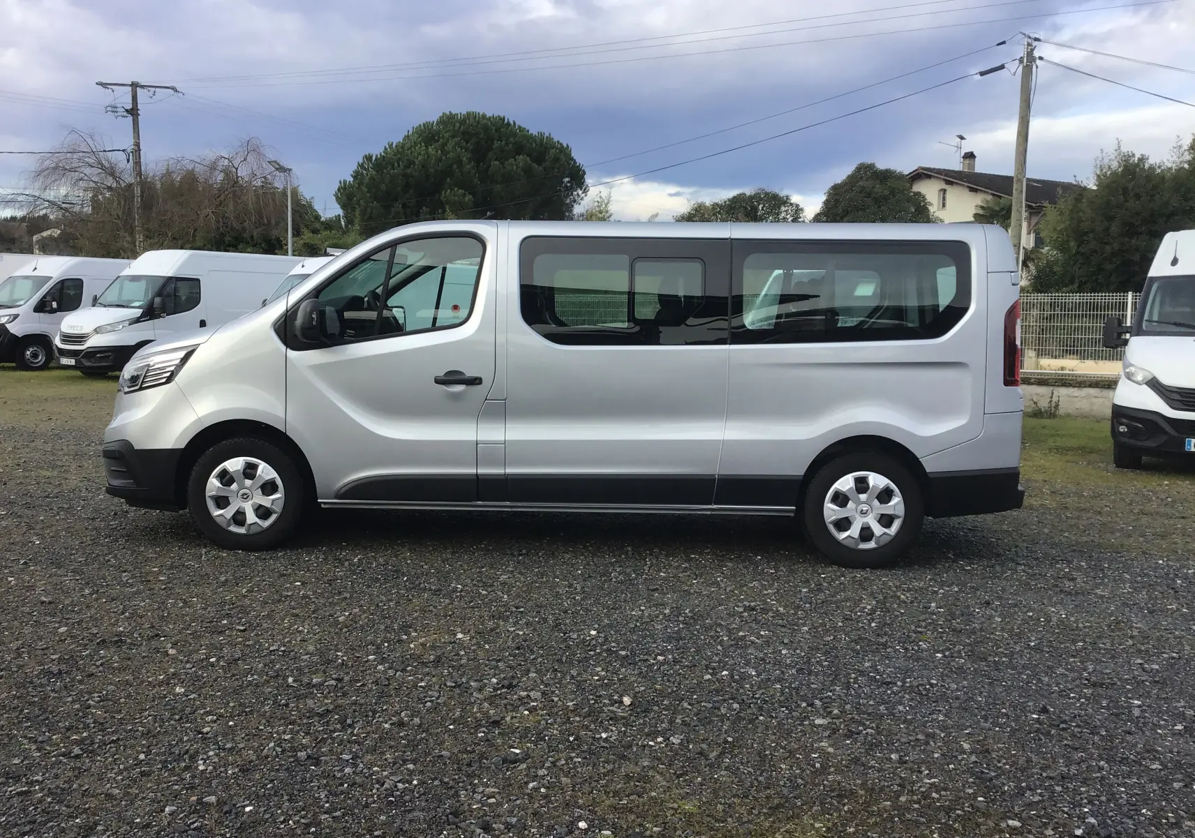 Profil côté gauche d’un Renault Trafic Combi gris clair métal 2023 avec grandes fenêtres et jantes acier.