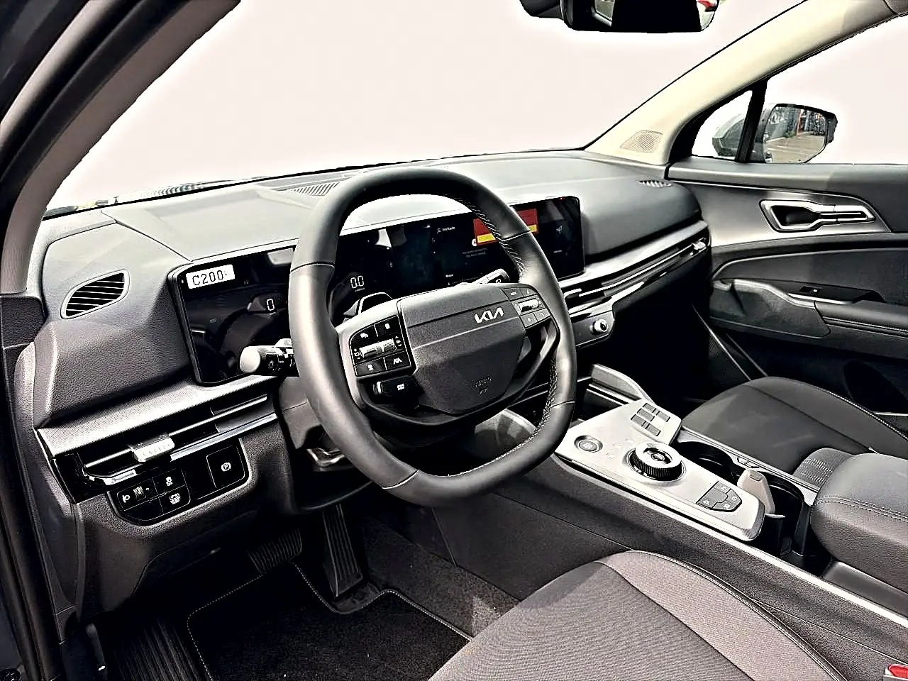 Intérieur du Kia Sportage 1.6 hybride 239, vue côté conducteur, volant cuir multifonction et écran tactile large.