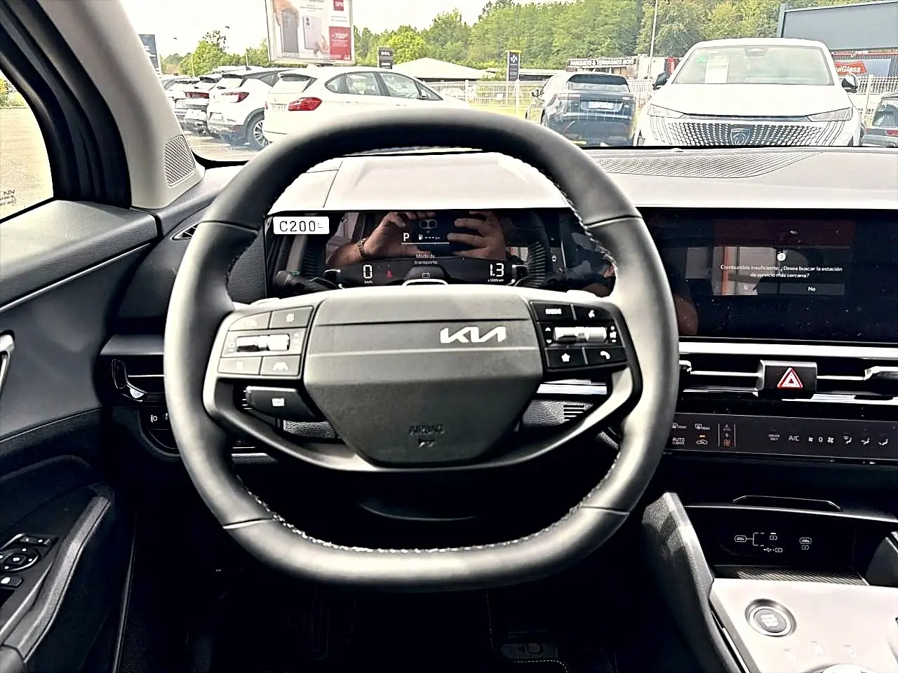 Vue intérieure centrée sur le volant cuir multifonction noir du Kia Sportage gris eclipse, avec tableau de bord numérique et écran tactile.