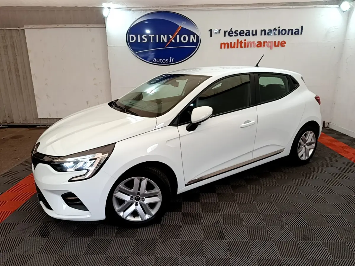 Renault Clio Business blanche vue de côté droit en intérieur, avec feux avant allumés et jantes alliage.