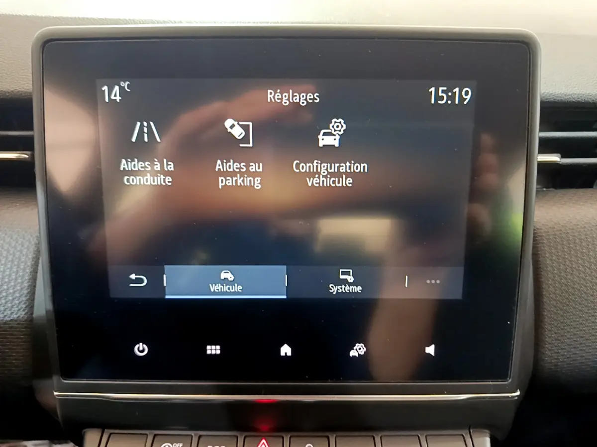 Écran tactile central de la Renault Clio Business blanc 2021 affichant les réglages d'aides à la conduite et au parking.