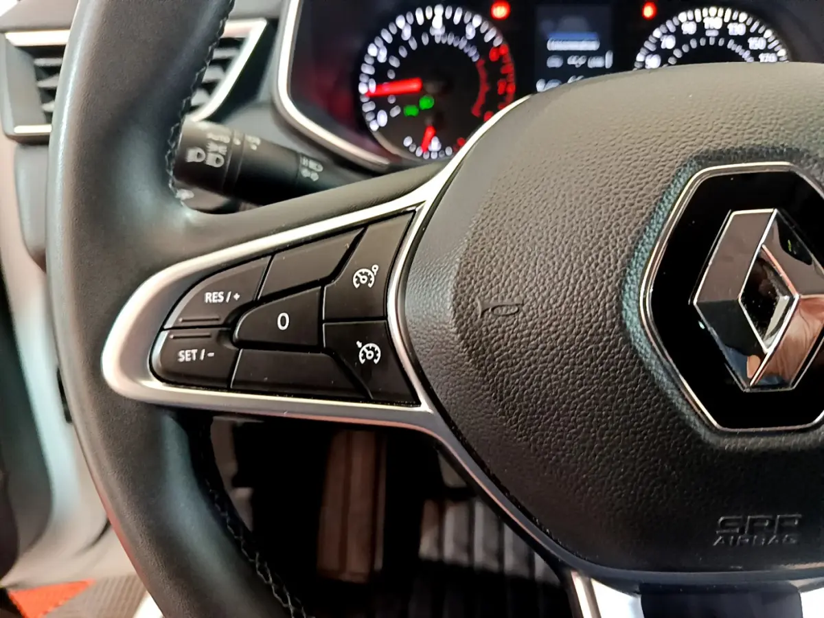 Gros plan sur le volant cuir noir de la Renault Clio Business 2021 avec commandes de régulateur de vitesse et logo central.