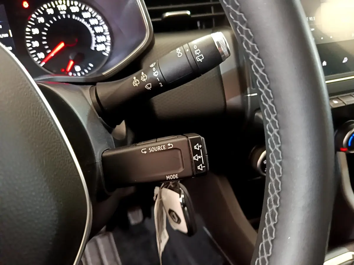 Gros plan sur le volant noir et la commande multifonction de la Renault Clio Business blanche de 2021.