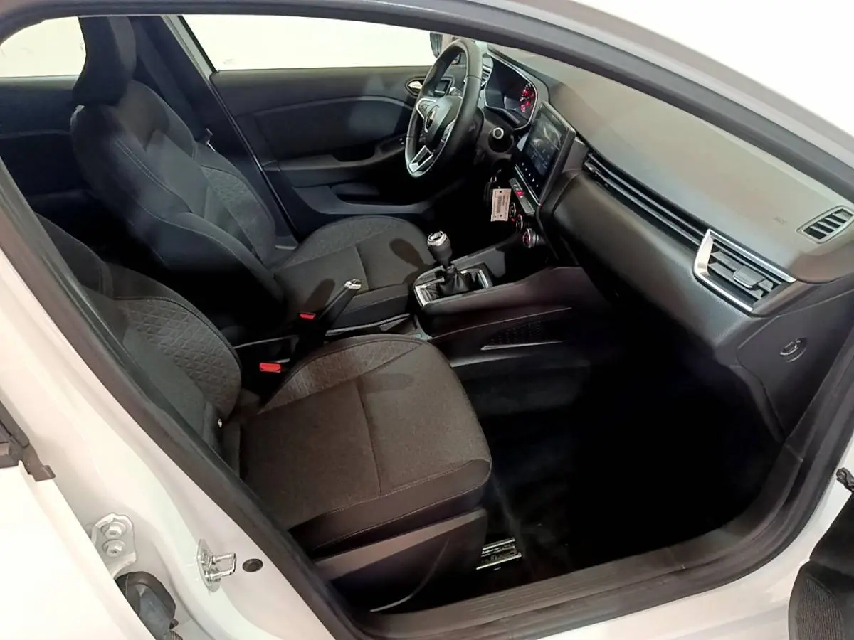Intérieur côté conducteur d'une Renault Clio Business blanche, montrant sièges noirs et tableau de bord avec écran tactile.