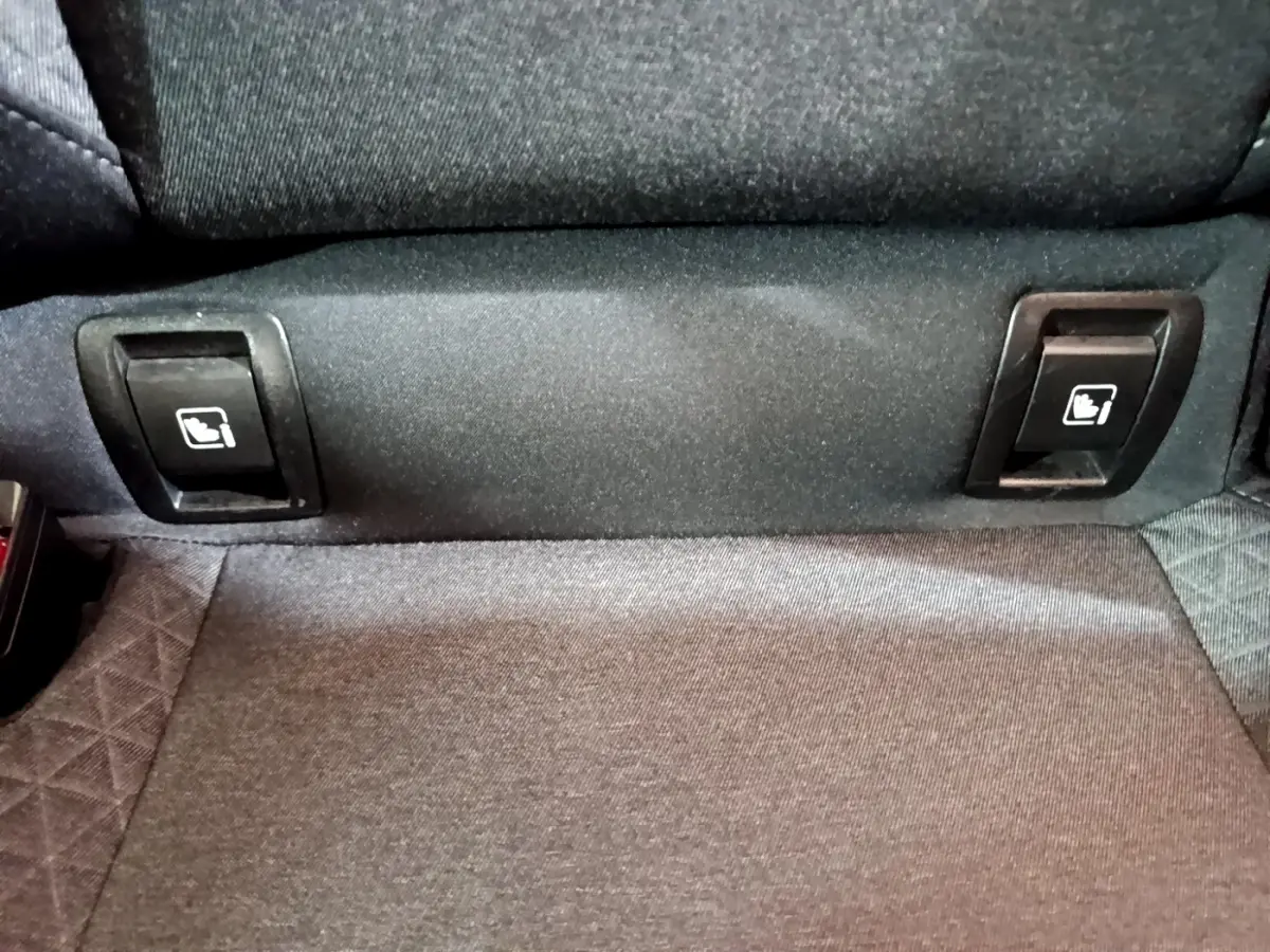 Gros plan sur les commandes de rabattement des sièges arrière en tissu gris de la Renault Clio Business blanche.