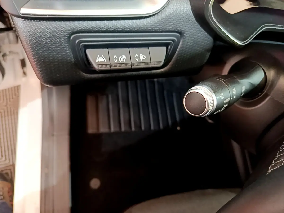 Gros plan sur les commandes d'assistance et la manette d'éclairage côté gauche dans l'habitacle d'une Renault Clio Business blanche.