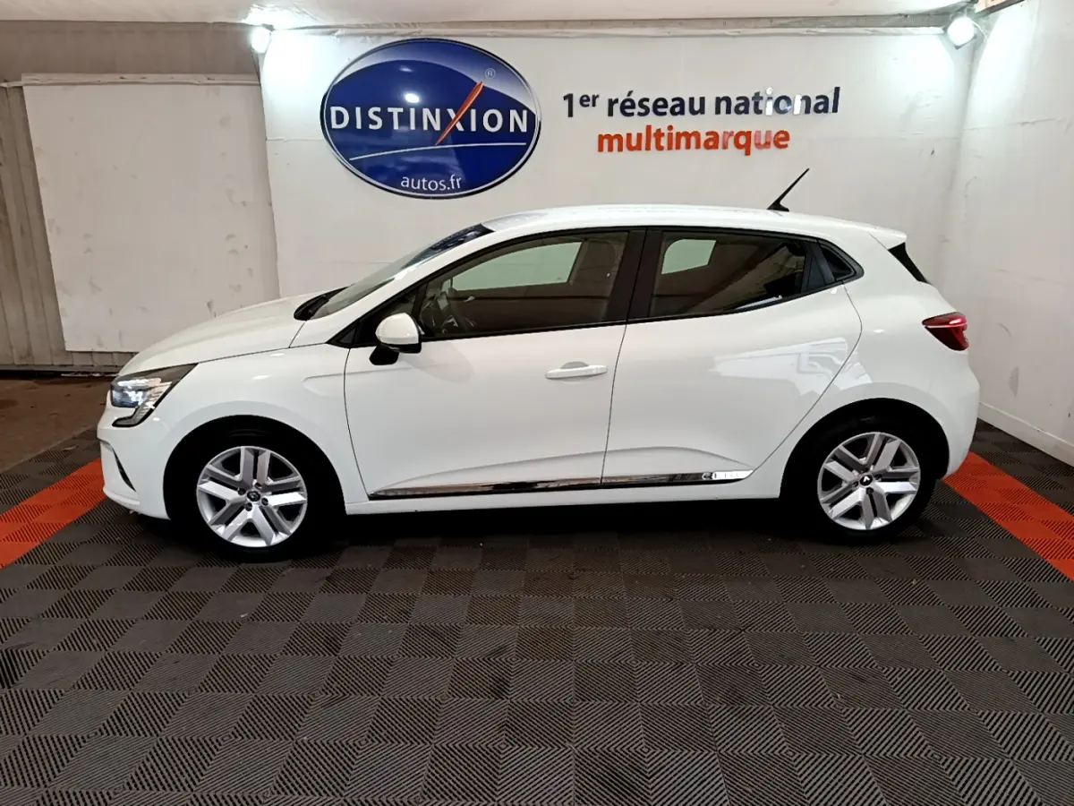 Profil droit d'une Renault Clio Business blanche 2021, avec jantes alliage et vitres teintées, en intérieur showroom.