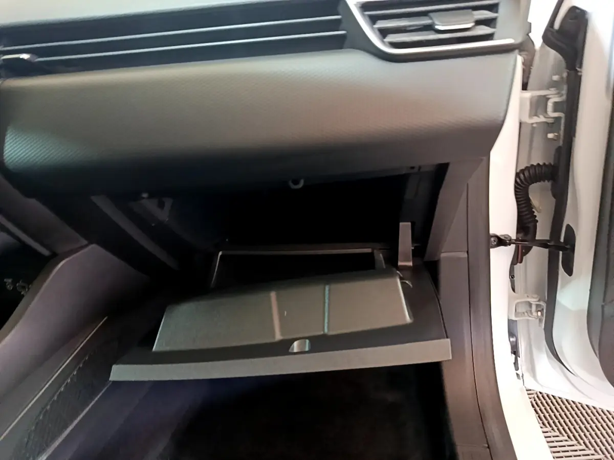 Vue rapprochée de la boîte à gants ouverte côté passager d'une Renault Clio Business blanche, intérieur noir.