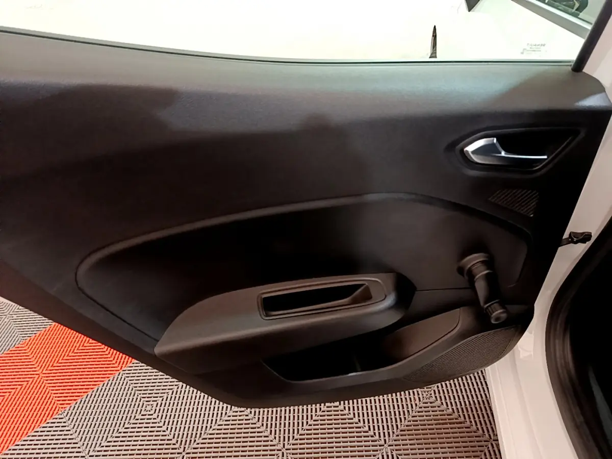 Vue intérieure de la porte côté droit noire d'une Renault Clio Business blanche avec manivelle de vitre visible.