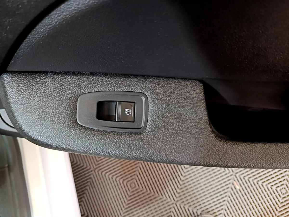 Bouton de commande de lève-vitre électrique côté conducteur sur portière noire d'une Renault Clio Business blanche 2021.