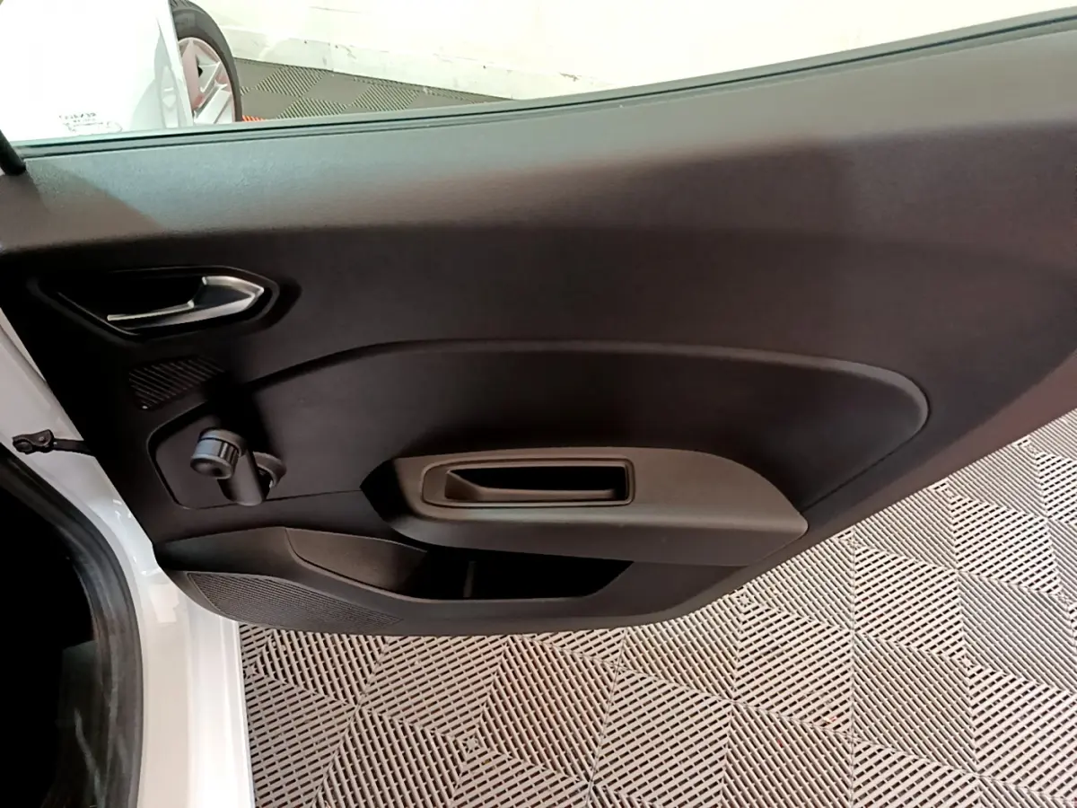 Vue intérieure de la porte côté gauche d'une Renault Clio Business blanche, avec poignée et commande manuelle de vitre.